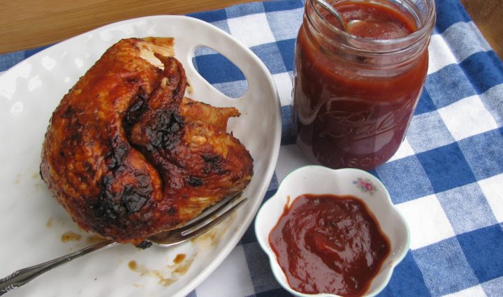 A plate of BBQ chicken featuring a jar of homemade BBQ sauce with bourbon