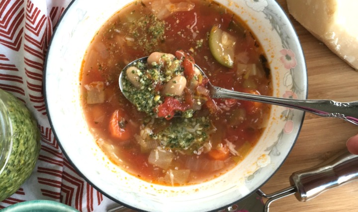 Warm bowl of minnestrone soup with basil pesto on the side