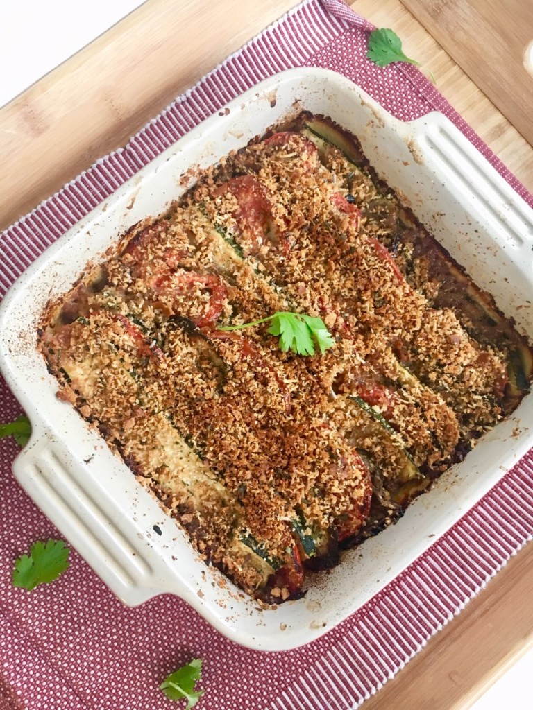 Eggplant, zucchini and tomato gratin fresh out of the oven in a square baking dish.