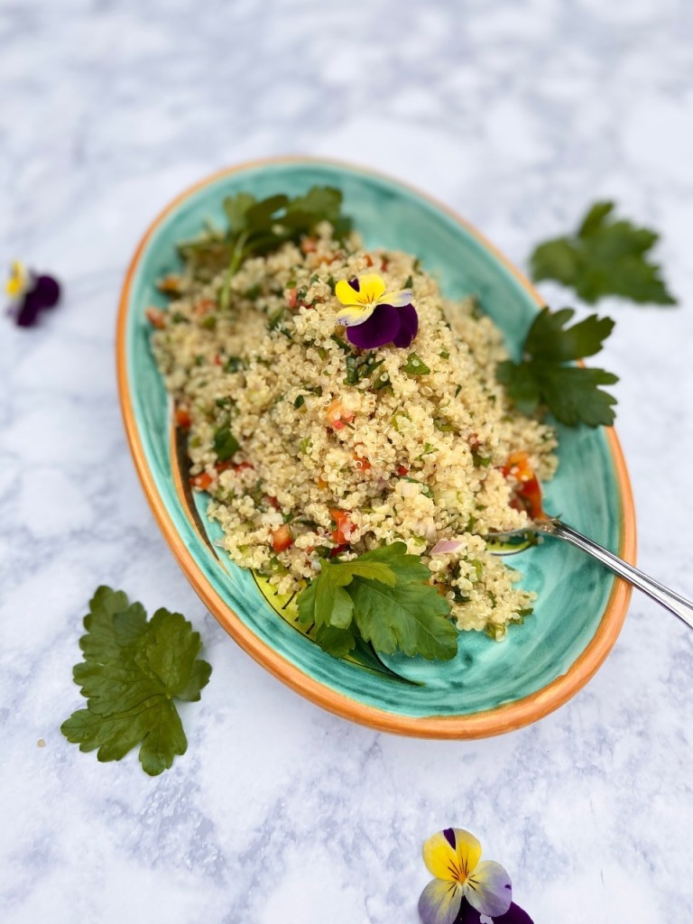Quinoa tabbouleh salad in an oval colorful bowl. Fresh parsley sprigs around it.