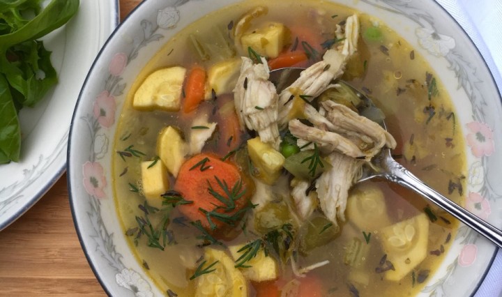 A bowl of slow cooker chicken soup featuring fresh veggies.