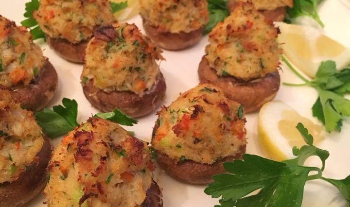 A platter of crab stuffed mushrooms fresh out of the oven. Served with lemon slices.