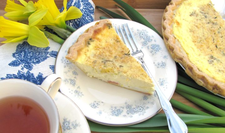 A slice of quiche lorraine with daffodils in the background