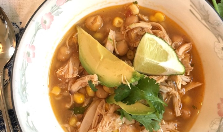 Spicy bowl of chipolte chicken chili topped with avocado, cilantro and lime.