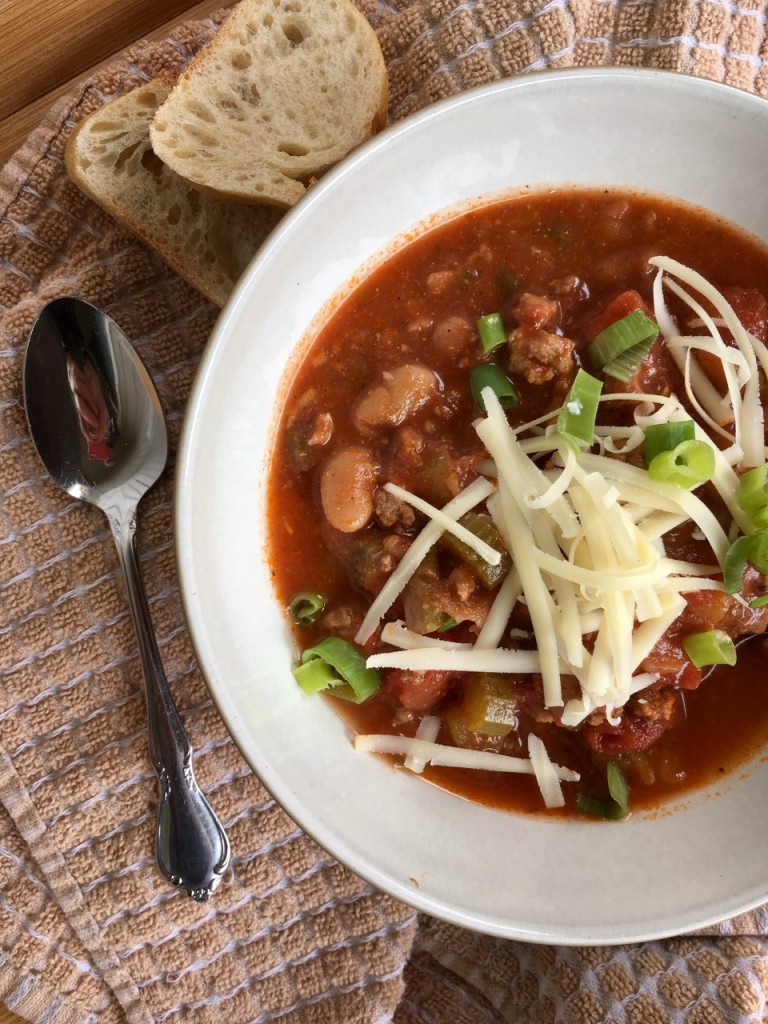 Close-up photo showing turkey chili with cannellini beans, celery and tomatoes